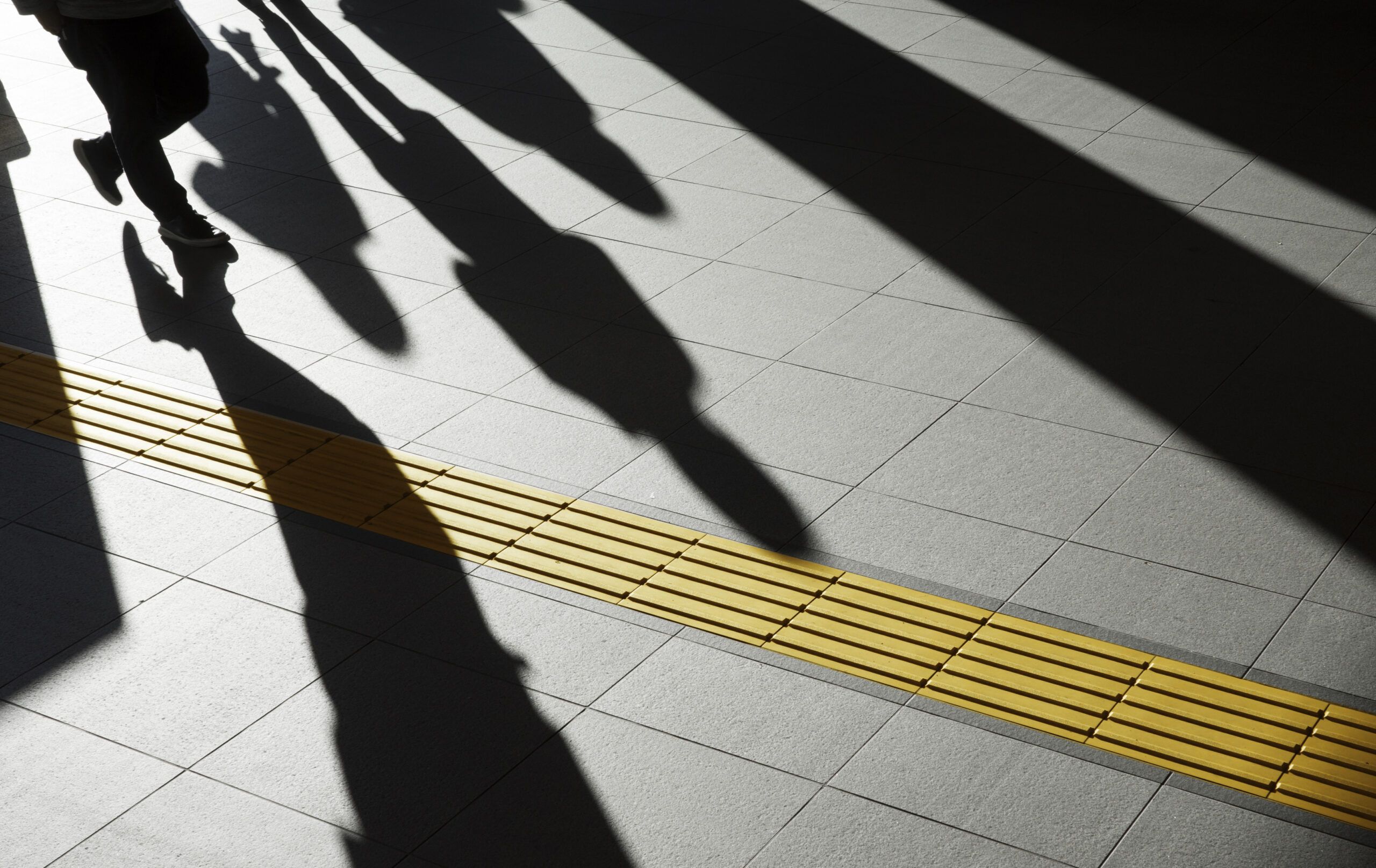 ombre di pendolari oltre la linea gialla